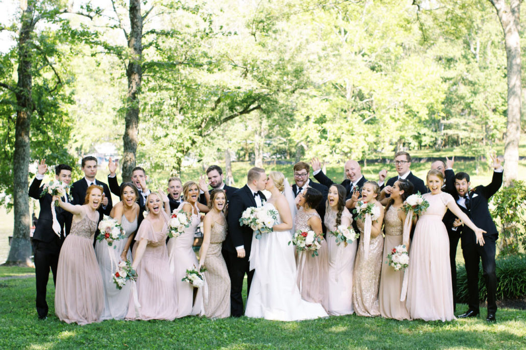 Bride and Groom Kissing Surrounded by Wedding Party