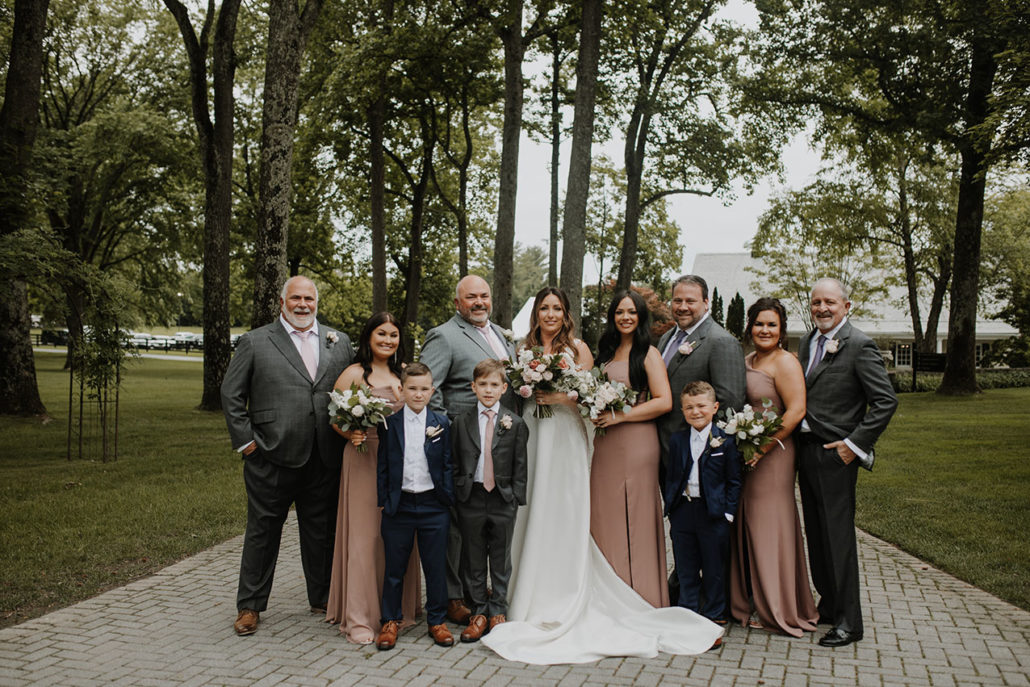 wedding party poses wearing muted terracotta dresses and gray suits