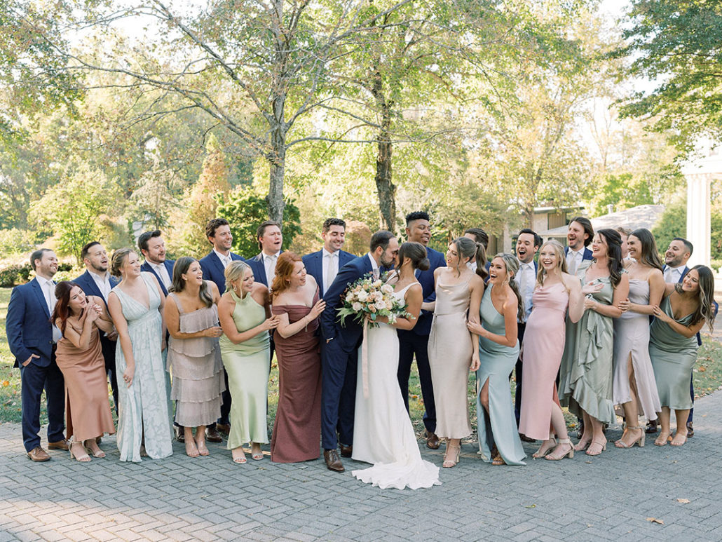 wedding party with groomsmen in blue suits and bridemaids in mix and match pastel gowns