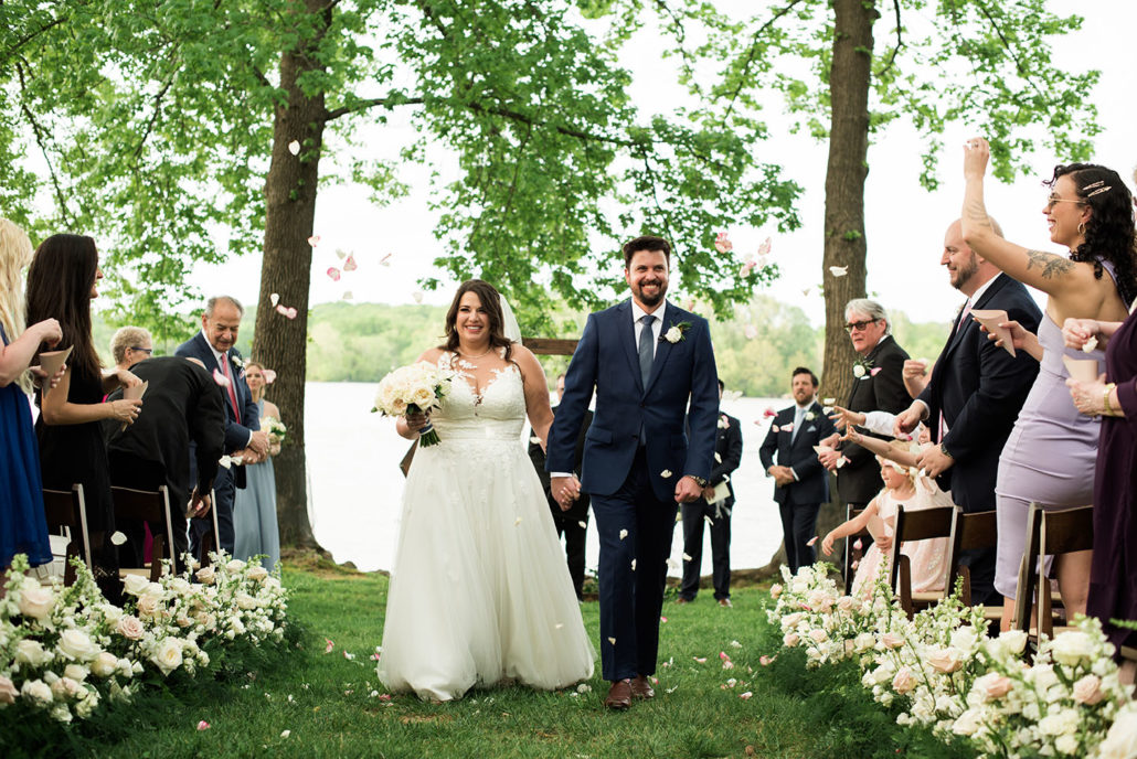 Bride and groom hold hands and smile after ceremony during wedding recessional