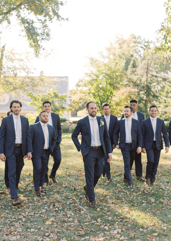 groomsmen walking in navy suits with pastel ties