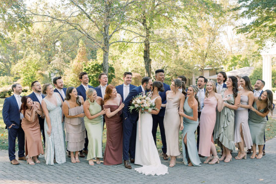 wedding party with groomsmen in blue suits and bridemaids in mix and match pastel gowns