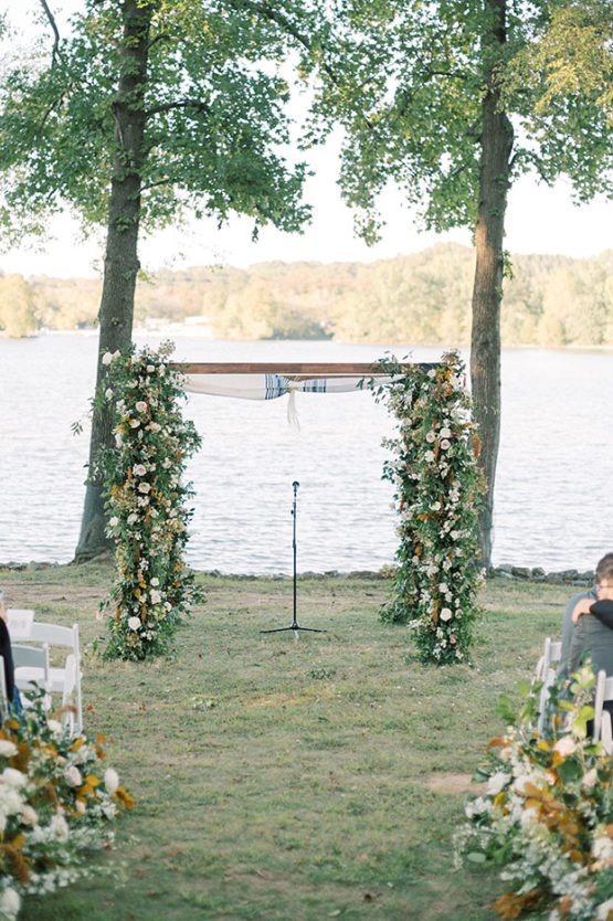 lakeside lawn ceremony with greenery decorated chuppah and aisle lined with florals