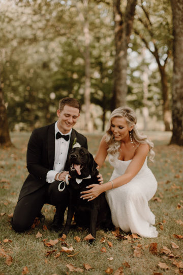Bride and groom pose with black lab under Willow Oak Canopy