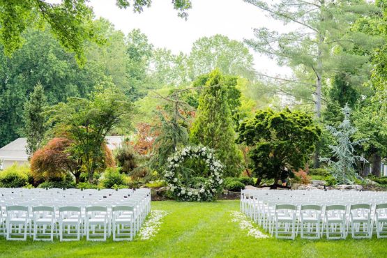 Ceremony with white seating and greenery floral circle
