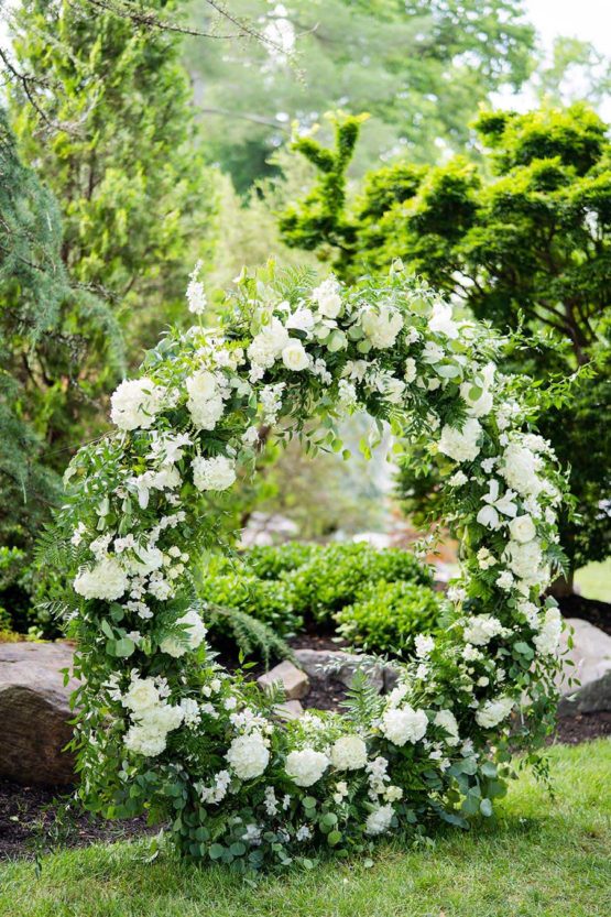 Round ceremony arch with white flowers and greenery