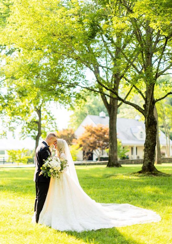 Andrea and Trevor pose for a photo under the tall green trees of the Willow Oak Canopy