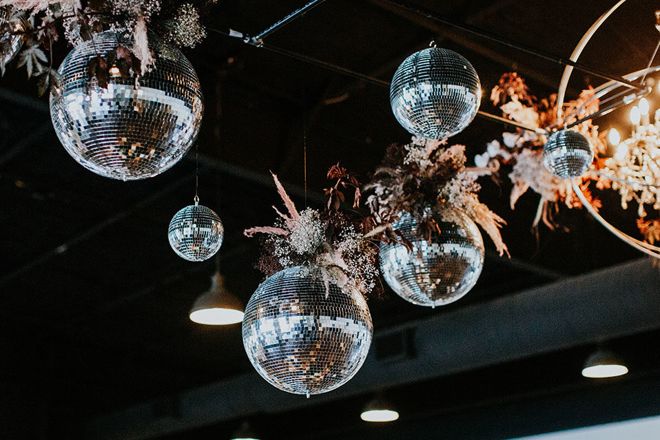disco balls hanging from the ceiling with pampas grass boho flower arrangements