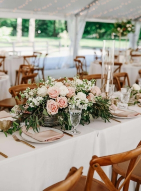 Tablescape for wedding reception on Sunset Terrace with large rose floral arrangement and tape candles with crystal classware