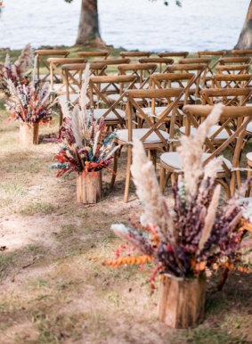Wedding ceremony setup with boho floral arrangements and wooden chairs