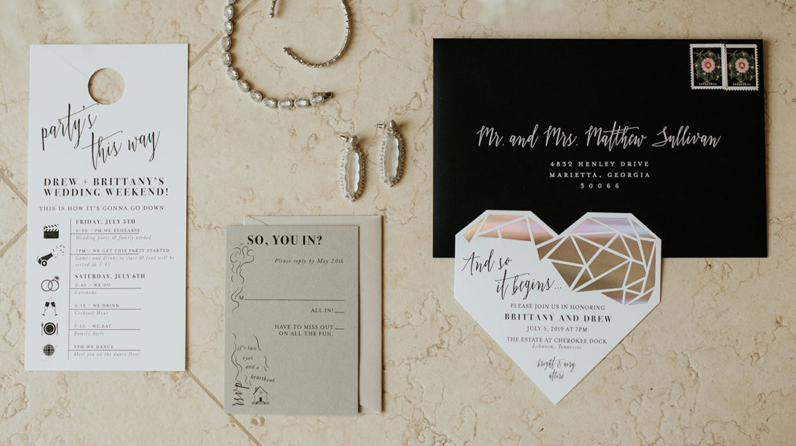 Modern black and white invitation suite flat lay with bridal jewelry