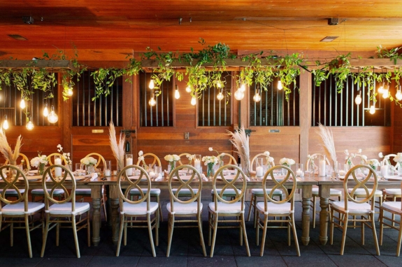 Rehearsal dinner table inside the Carriage House Stables with dried pampas grass arrangements and greenery