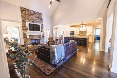 Living room with leather couch and fireplace with open concept kitchen inside Gatehouse 155