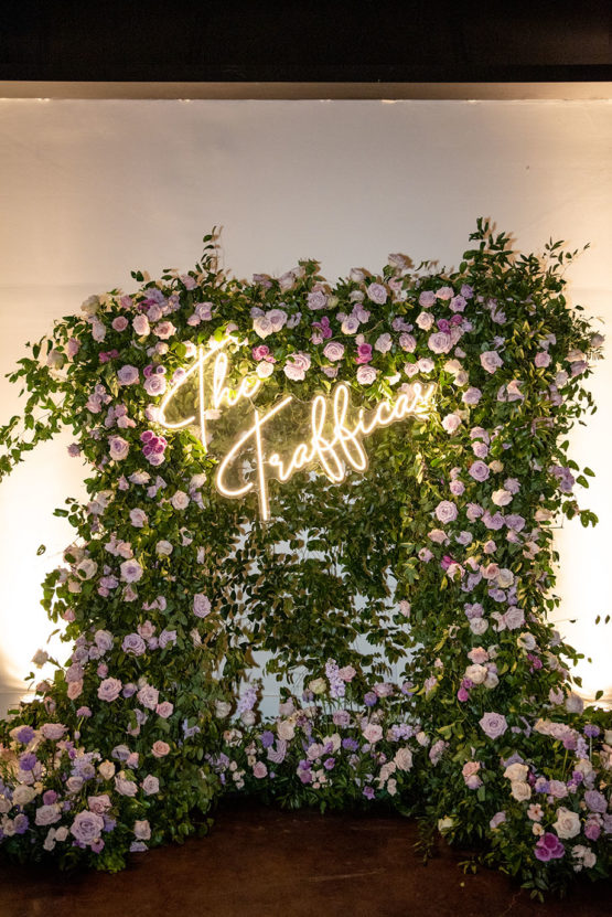 Large Floral Arch Backdrop with Purple Flowers with a neon sign