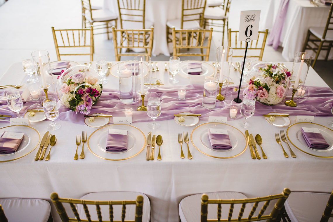 Bright and Airy Wedding Tablescape with Neutral White Linens Purple Napkins Gold Details and Bright Colorful Spring Floral Centerpieces