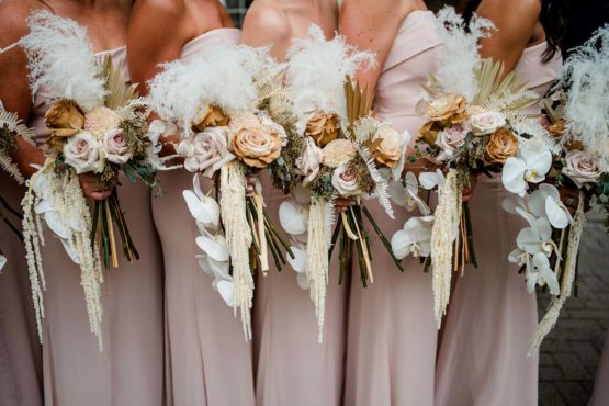 Boho bridesmaids bouquets with dried flowers, white orchids, pampas grass, and earthy pastel blooms
