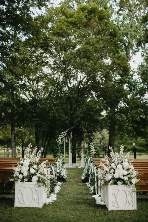 Ceremony setup under the Willow Oak Canopy with large white floral arrangements and flower petal-lined aisle