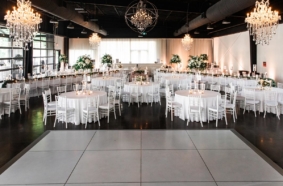 All white wedding reception setup inside Lakeview Event Center with chandeliers and dance floor