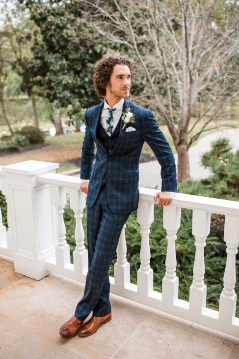 Groom posing on mansion's front porch