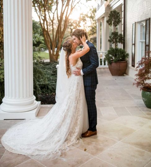 Bride and groom kiss on mansion's front steps