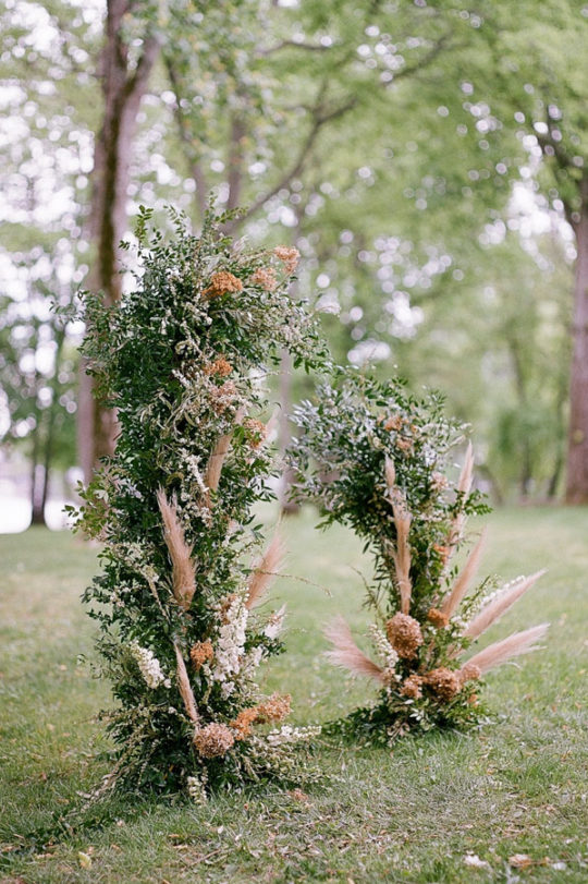 Freestanding open ceremony arch created with greenery and pampas on the Lakeside Lawn