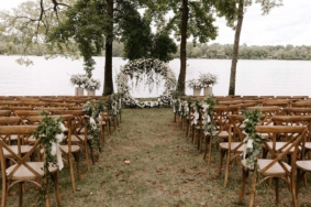 Wedding ceremony setup on Lakeside Lawn with wooden chairs and round white floral ceremony arch
