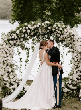 Bride and groom kiss in front of round ceremony arch on Lakeside Lawn