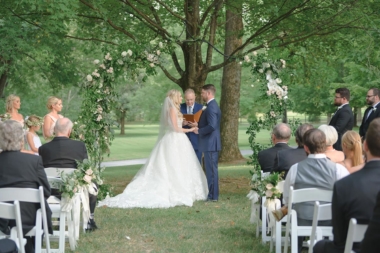 Bride and groom holding hands during their ceremony ceremony in front of an asymmetrical greenery arch under the Willow Oak Canopy