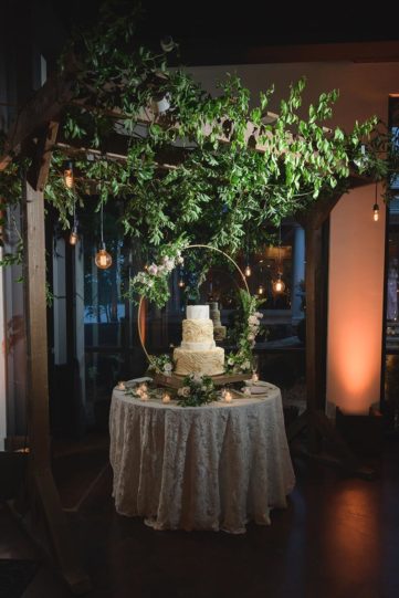 Extravagant Wedding Cake Display with Greenery and Gold Arch Adorned with Roses