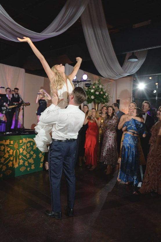 Groom holds bride on dance floor during reception