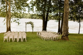 Lakeside Lawn ceremony setup with white chairs and ceremony arch adorned with flowers