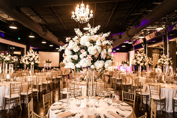 Wedding reception tables inside Lakeview Event Center with tall floral arrangement on acrylic stand