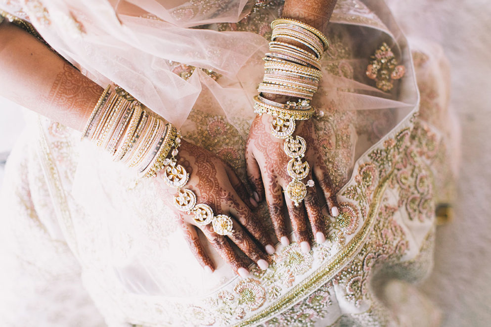 Niyomi's hands with traditional henna tattoos and bridal bangles
