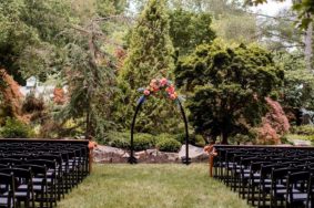 Ceremony setup in Serenity Gardens with black arch and vibrant bold flowers