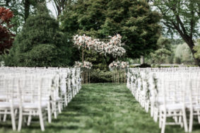 Ceremony setup in Serenity Gardens with white chairs and brass ceremony arch with pastel and white roses