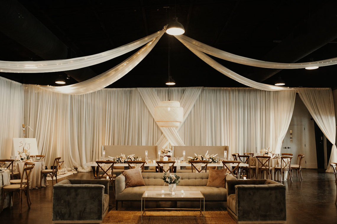 indoor wedding reception with floor to ceiling draping around the entire space along with lounge seating set in the middle
