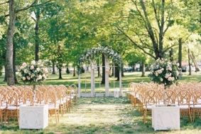 Wedding ceremony setup under Willow Oak Canopy with white flowers and vintage windows as ceremony backdrop