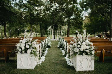 Ceremony setup in Willow Oak Canopy with pew seating and large white floral arrangements