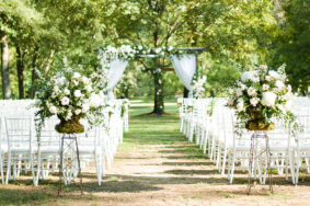 Wedding ceremony setup under Willow Oak Canopy with large floral arrangements and white chairs